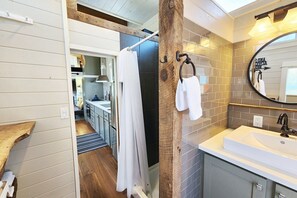 Un baño moderno con un espejo grande, un lavabo y una zona de ducha.