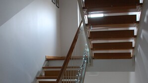 En trappe med trætrapper og hvide gelændere, der fører til en etage ovenover.