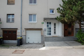 A two-story residential building with a white garage door, a small front porch, and a wooden door. - Apartments Peter (Ljubljana)