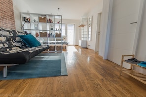 A modern living room with a sofa, a bookshelf, and a wooden floor. - Apartments Peter (Ljubljana)