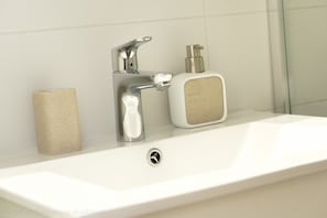 A bathroom sink with a chrome faucet, a soap dispenser, and a roll of toilet paper. - Apartments Peter (Ljubljana)