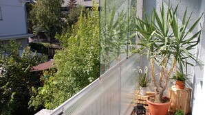 En balkon med plantekasser, et lille bord og en lygte.