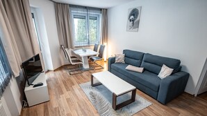 A modern living room with a sofa, coffee table, and dining area. - Apartamenty Sun & Snow Nad Potokiem (Krynica-Zdroj)