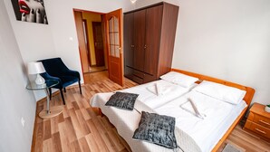A neatly arranged bedroom with a bed, a chair, a wardrobe, and a lamp. - Apartamenty Sun & Snow Nad Potokiem (Krynica-Zdroj)