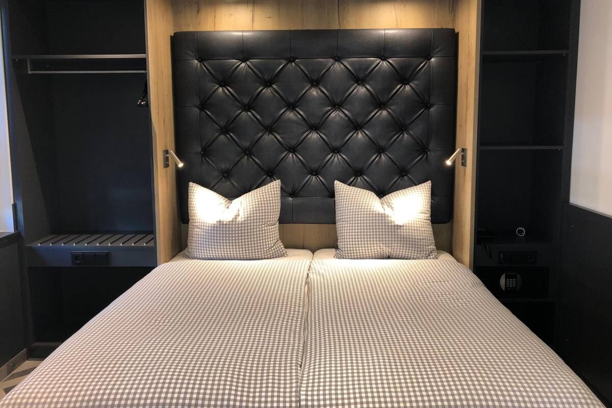A bedroom with a tufted headboard, checkered bedding, and bedside tables with lamps.