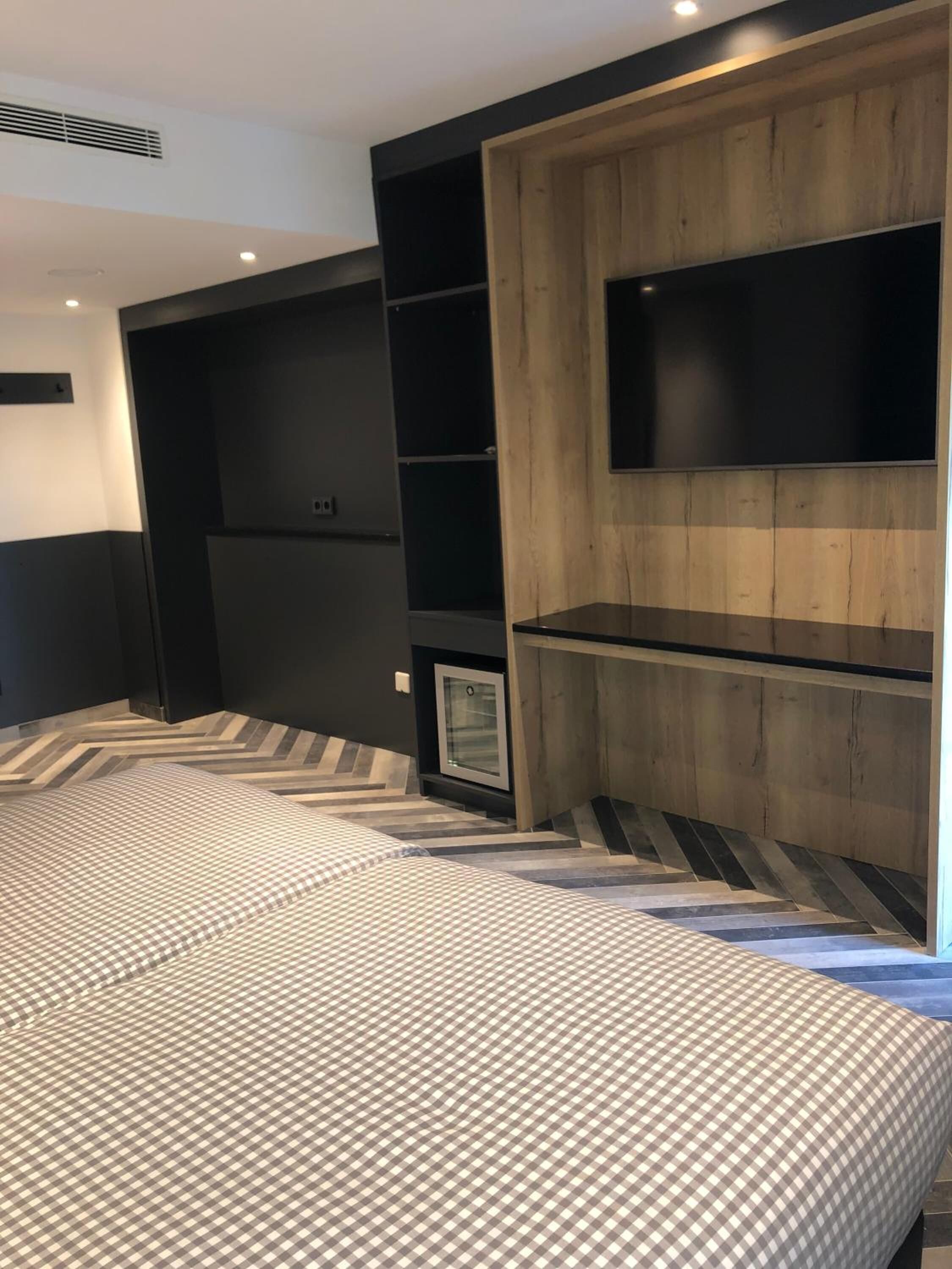 Una camera da letto moderna con un ampio letto, televisione integrata e una piccola area salotto.