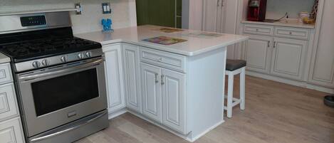 A kitchen with white cabinetry, a stainless steel stove, and a microwave.