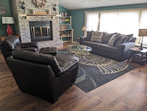 Cozy living room with a fireplace, leather armchairs, and a sofa with patterned cushions.