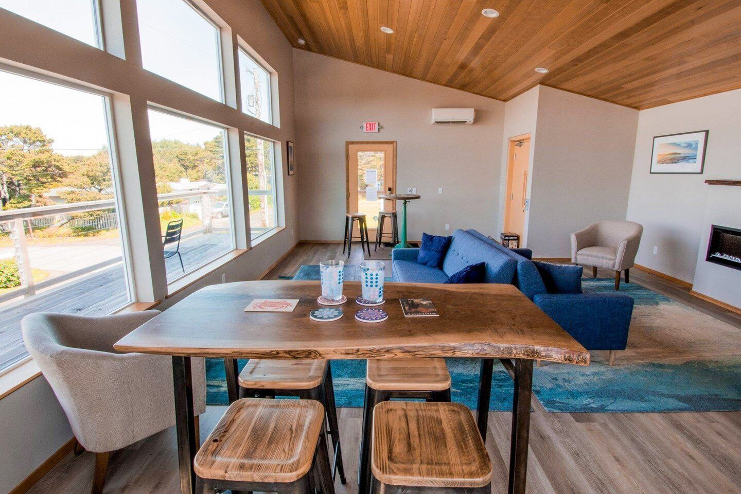 A modern interior with a wooden table and stools, a blue sofa, and a fireplace.