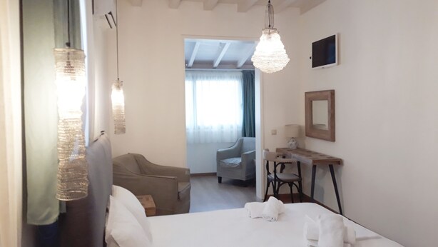 A hotel room with a bed, a desk, a chair, and a hanging light fixture. - Lefkada Princess (Lefkada)
