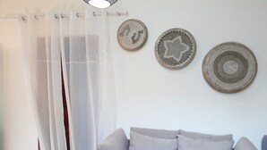 A living room with a light-colored sofa, sheer curtains, and two woven wall decorations. - Lefkada Princess (Lefkada)