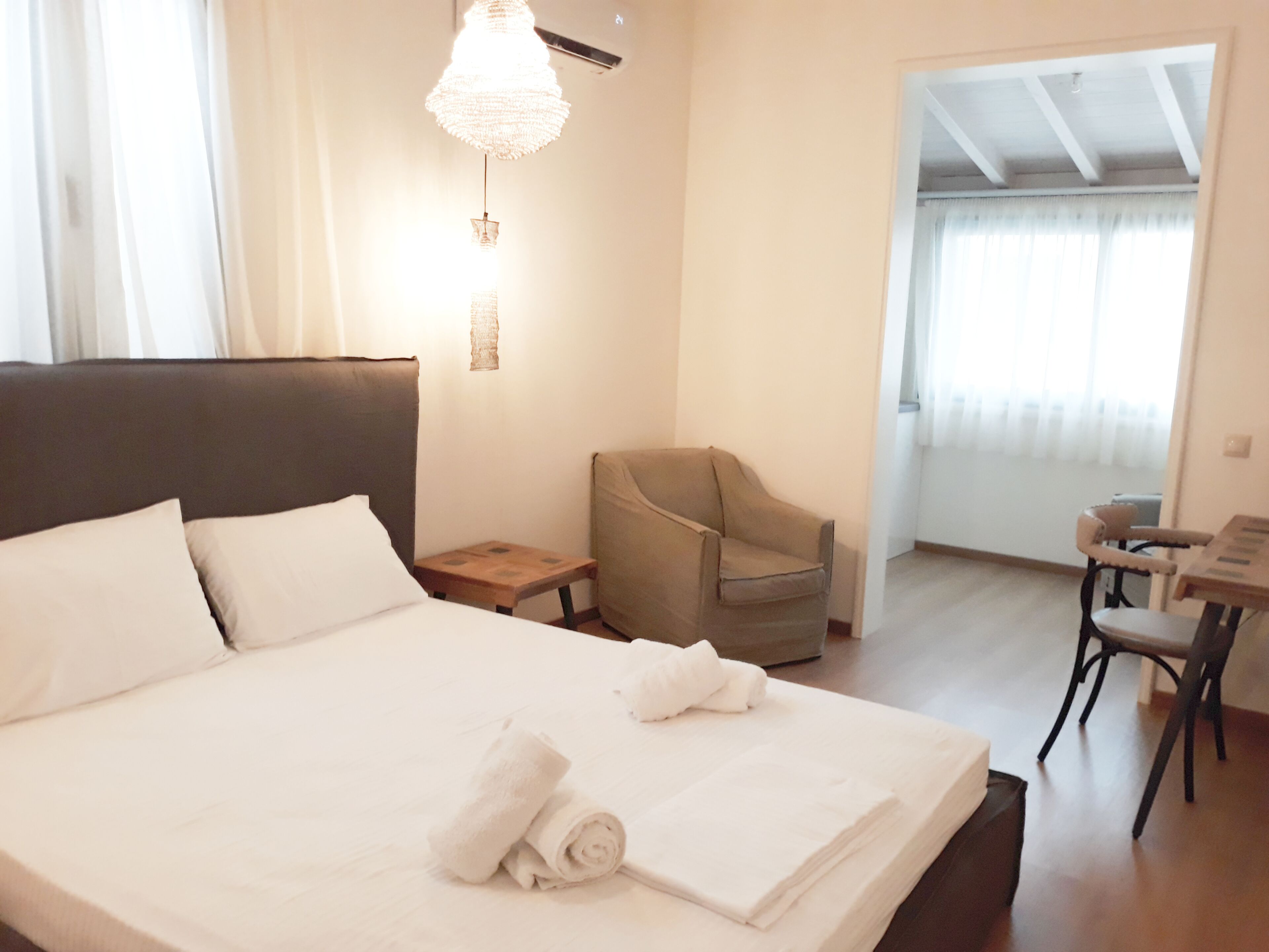 Una habitación de hotel con una cama grande, una silla, una mesita y un candelabro.