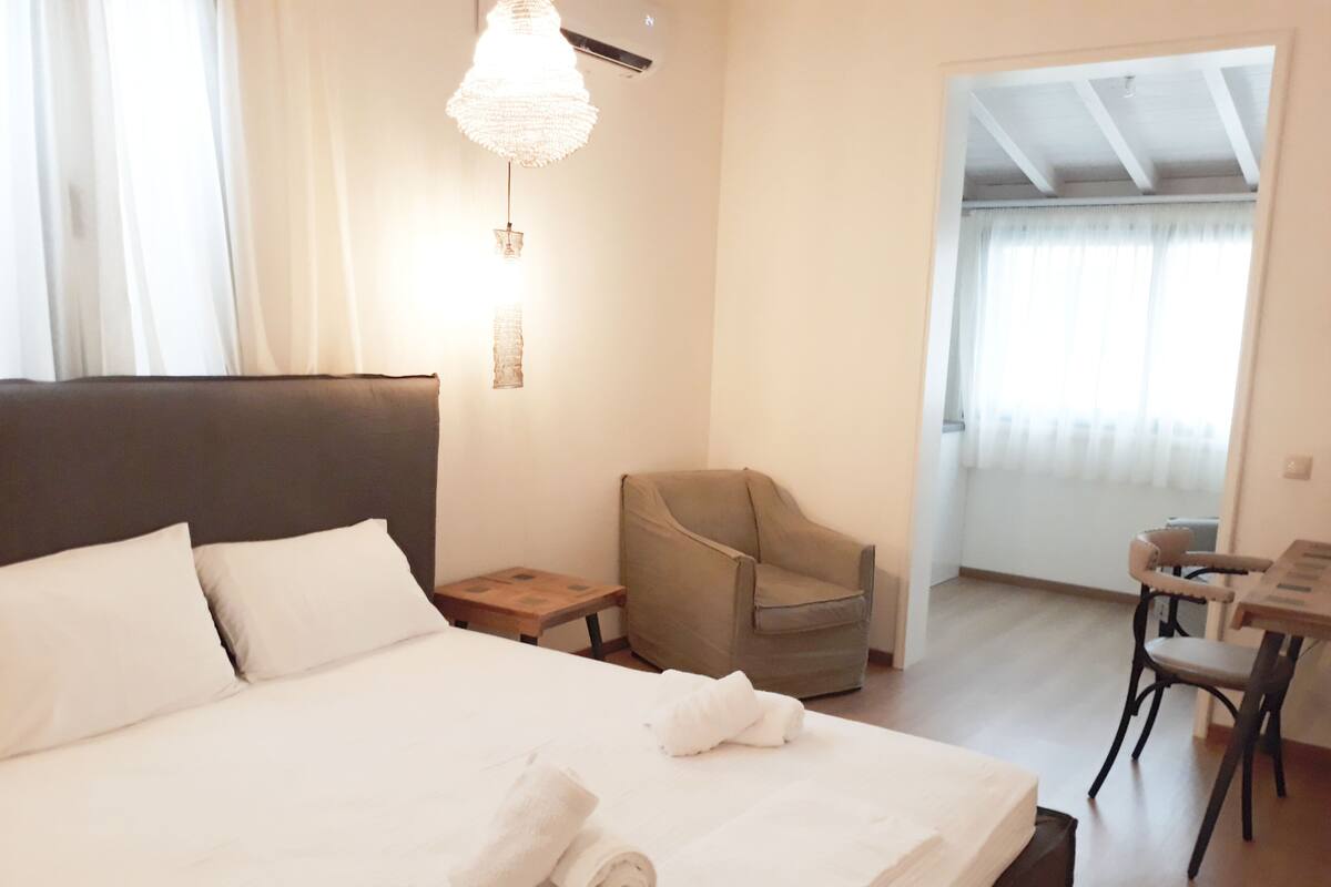A hotel room with a large bed, a chair, a small table, and a chandelier.