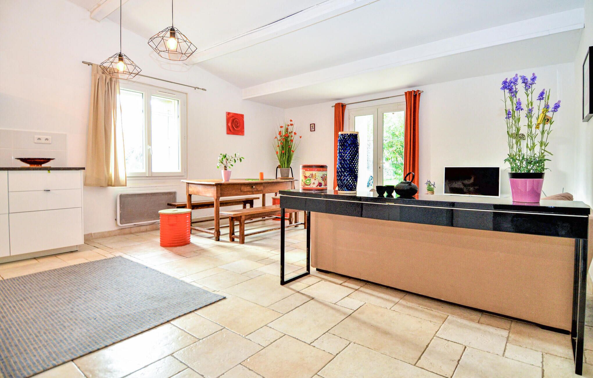 A modern kitchen with a central island, a dining area with a table and chairs, and a large window with curtains.