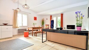 Una cucina moderna con isola centrale, un'area pranzo con tavolo e sedie e un'ampia finestra con tende.
