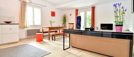 A modern kitchen with a central island, a dining area with a table and chairs, and a large window with curtains.