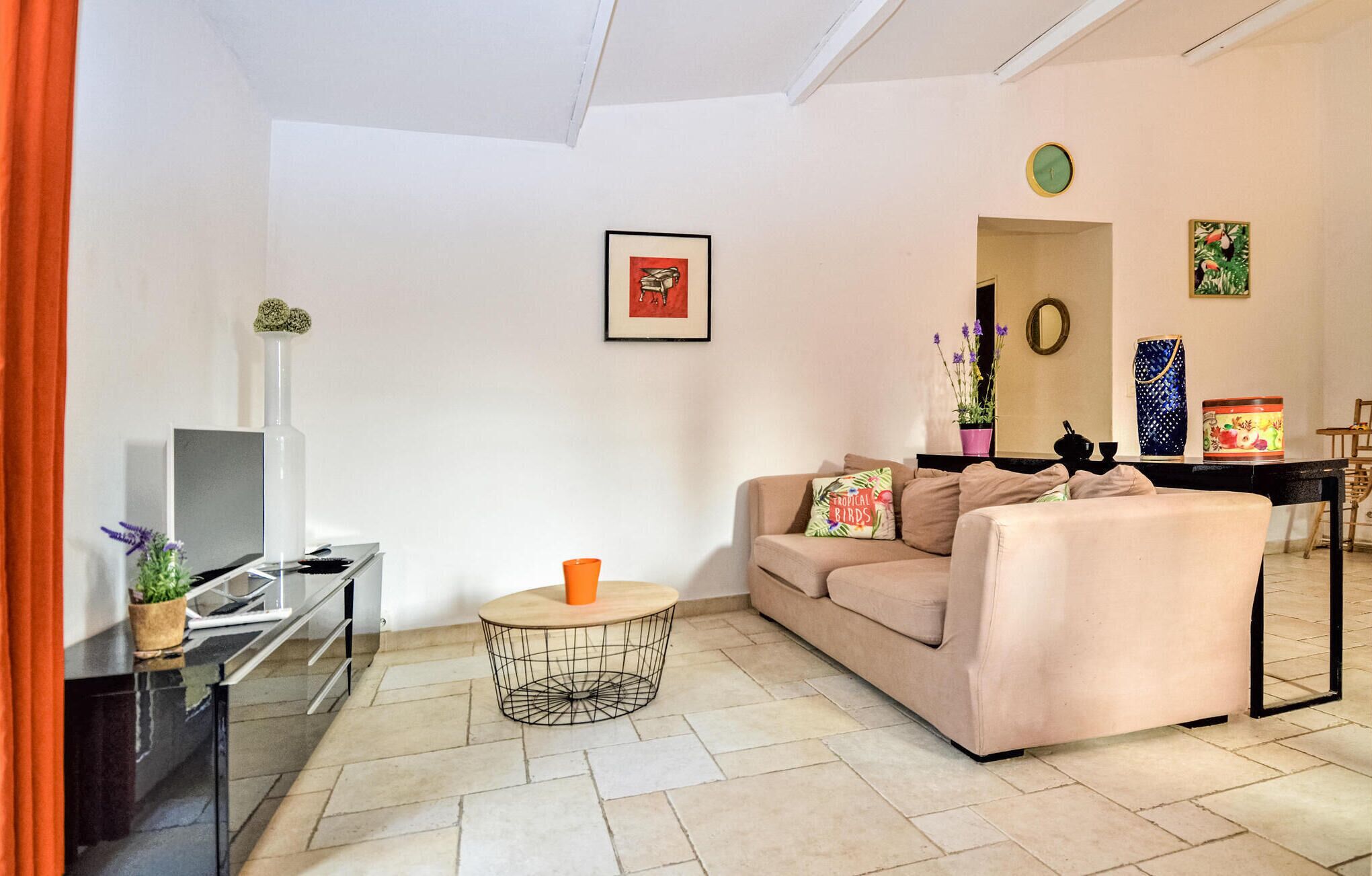 Sala de estar com sofá, mesa de centro, televisão e área de jantar com mesa e cadeiras.