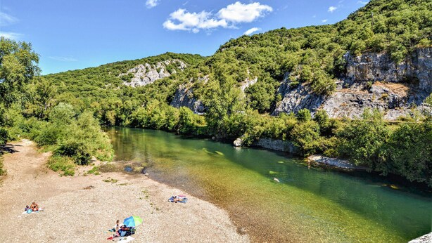 Un fiume circondato da una vegetazione rigogliosa e imponenti scogliere rocciose.
