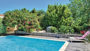 Una piscina con parete in pietra e lettini.