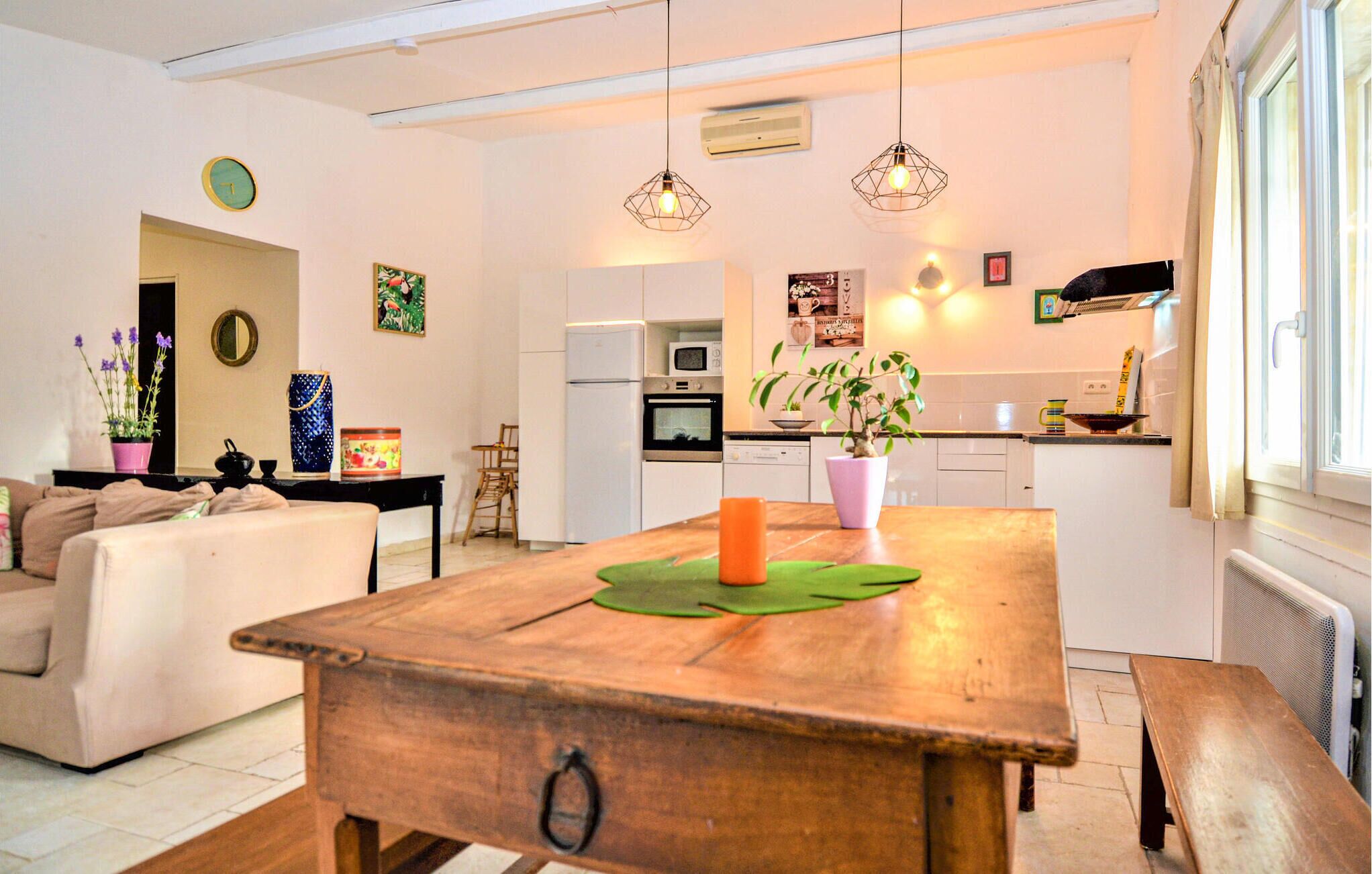 A modern kitchen with white cabinets, a microwave, and a stove. There is a dining table with a green placemat and a candle.