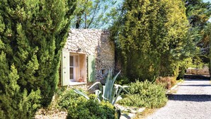 Un edificio in pietra con una finestra, immerso nel verde e con un vialetto sterrato.
