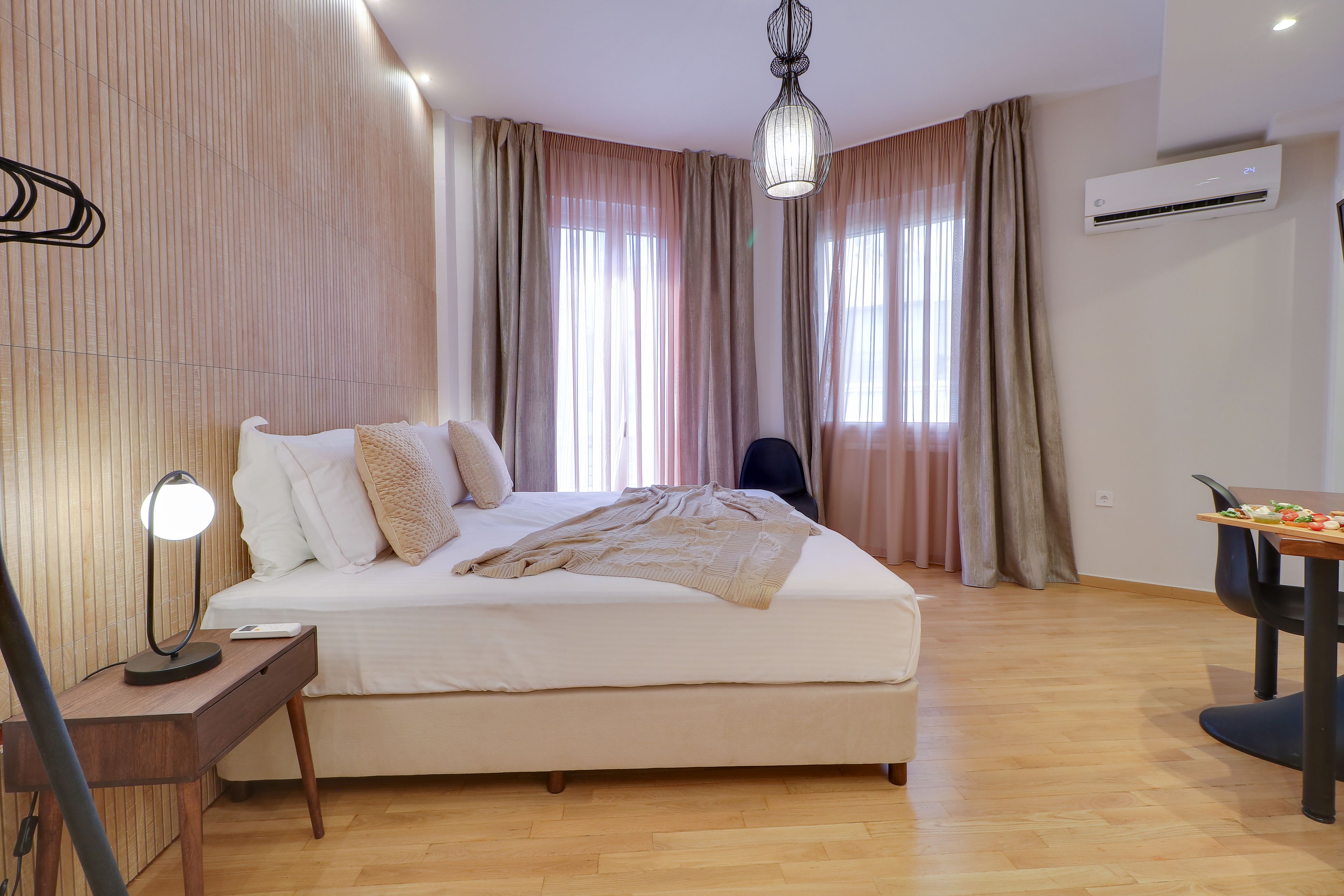 Un dormitorio moderno con cama, mesita de noche, lámpara y un área de comedor con mesa y sillas.