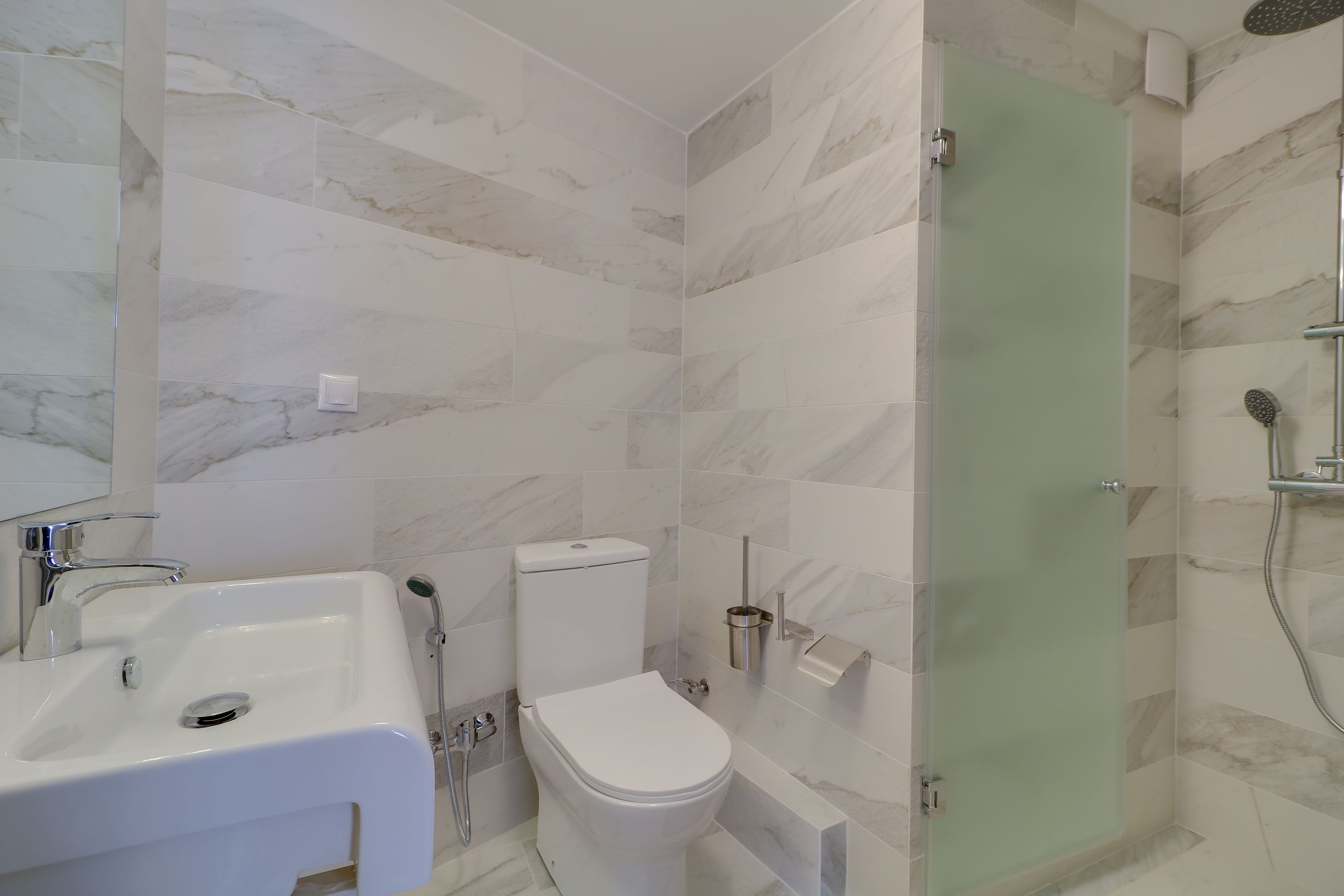 Une salle de bain moderne avec un lavabo blanc, des toilettes et une douche à parois de verre.