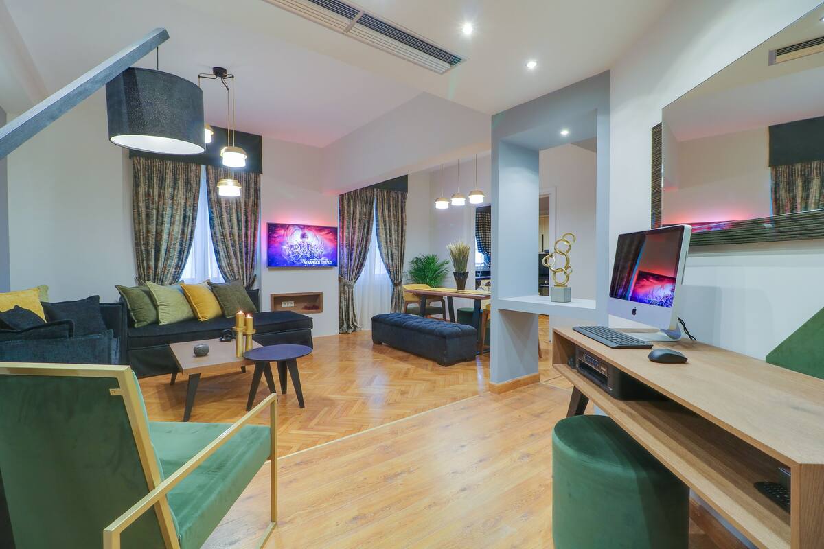 A modern living room with a sofa, coffee table, and a desk with a computer.