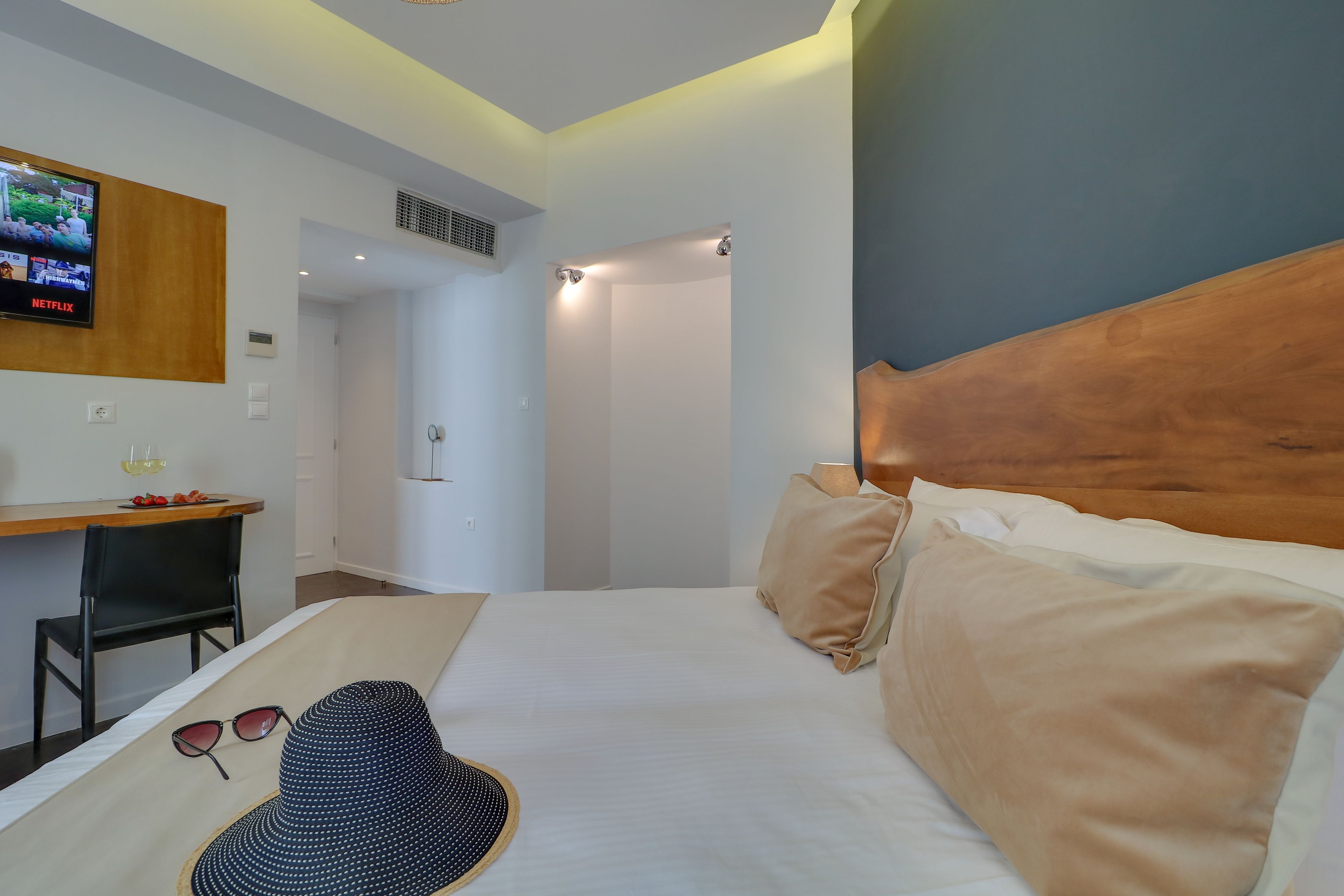 Une chambre d’hôtel équipée d’un lit, d’un bureau, d’un téléviseur fixé au mur et d’un espace douche.