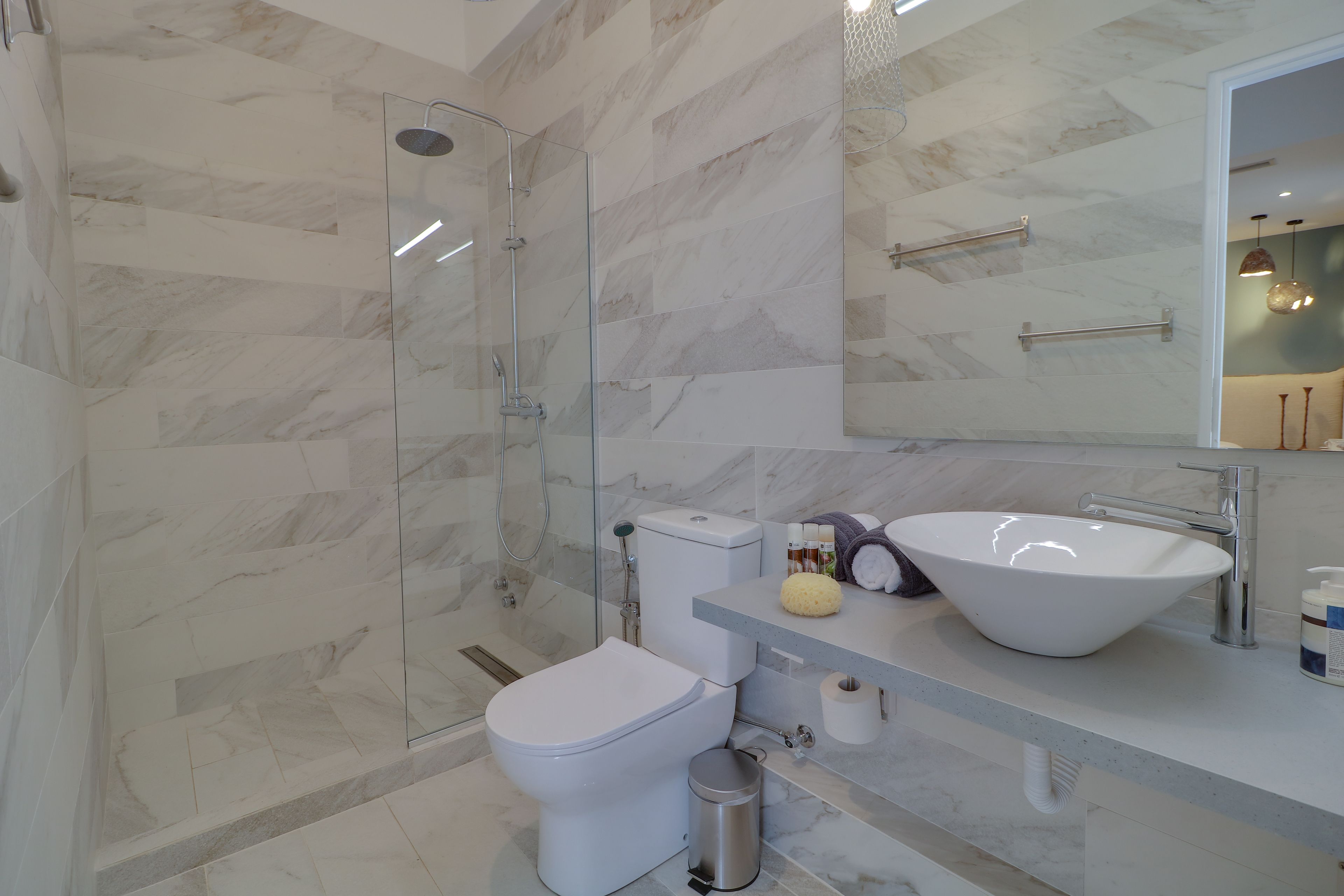 A modern bathroom with a glass-enclosed shower, a white toilet, and a large vessel sink.