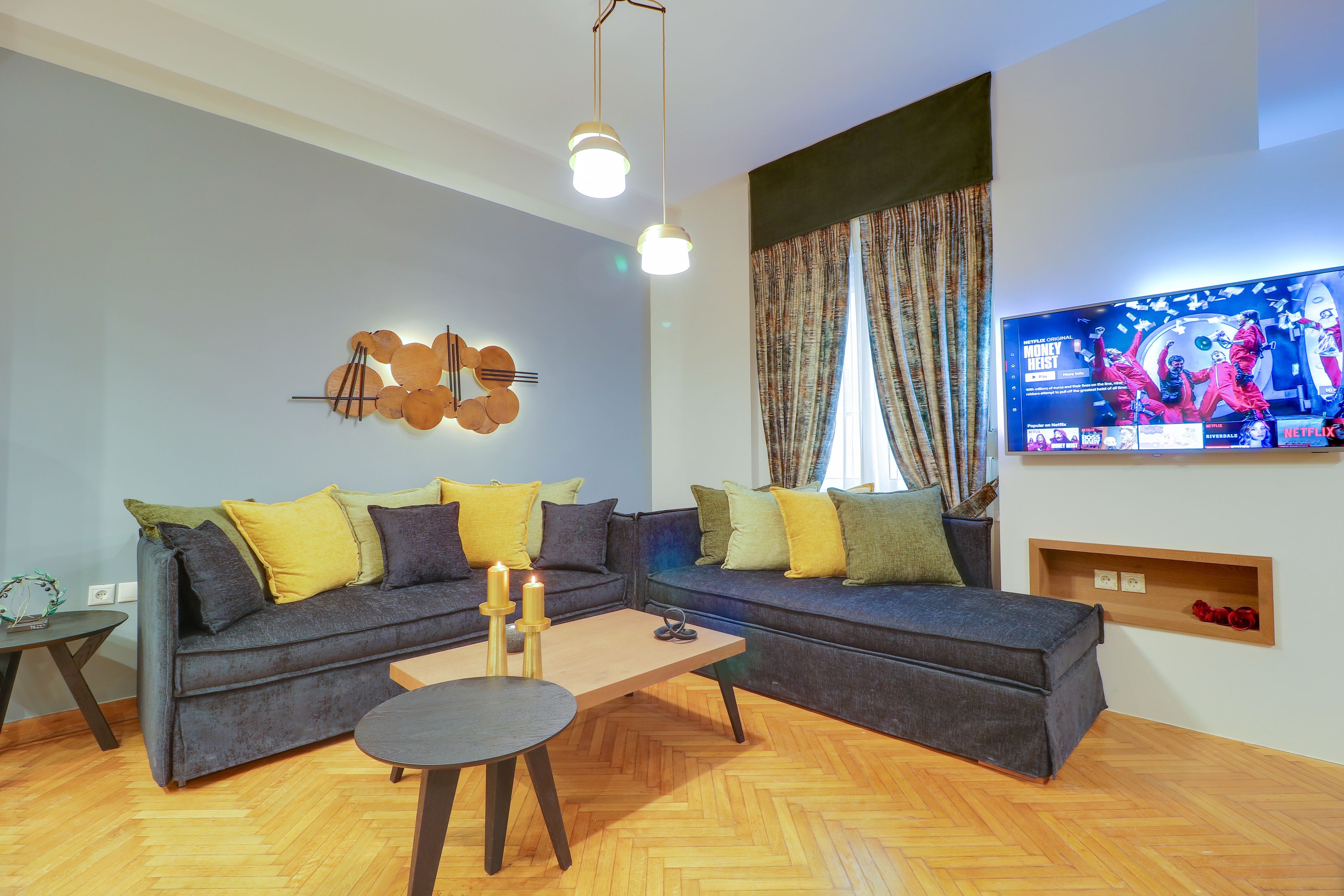 A modern living room with a sectional sofa, a coffee table, and a flat-screen TV mounted on the wall.