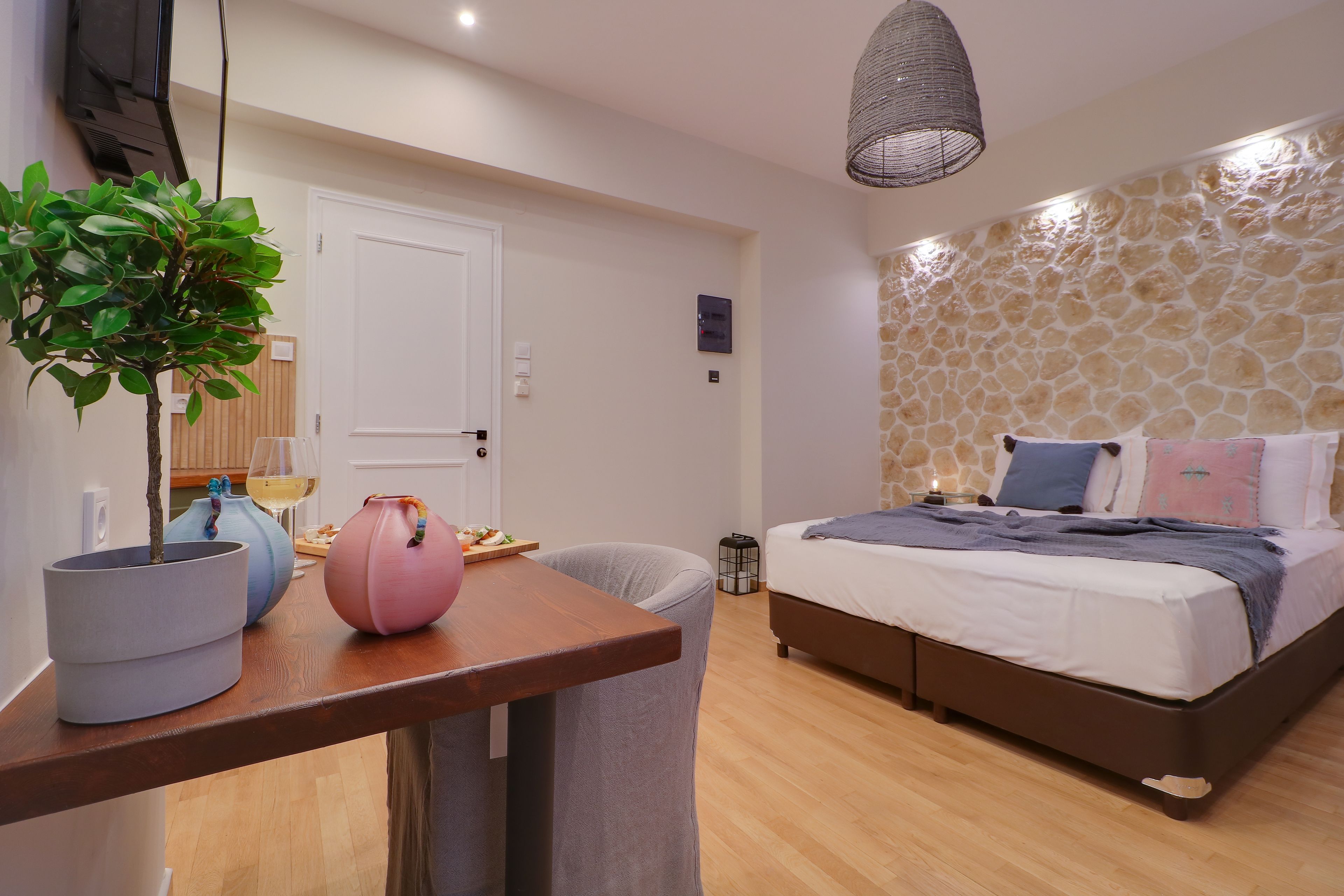 Une chambre à coucher avec un lit, un bureau agrémenté d’une plante en pot, une chaise et un mur en pierre.