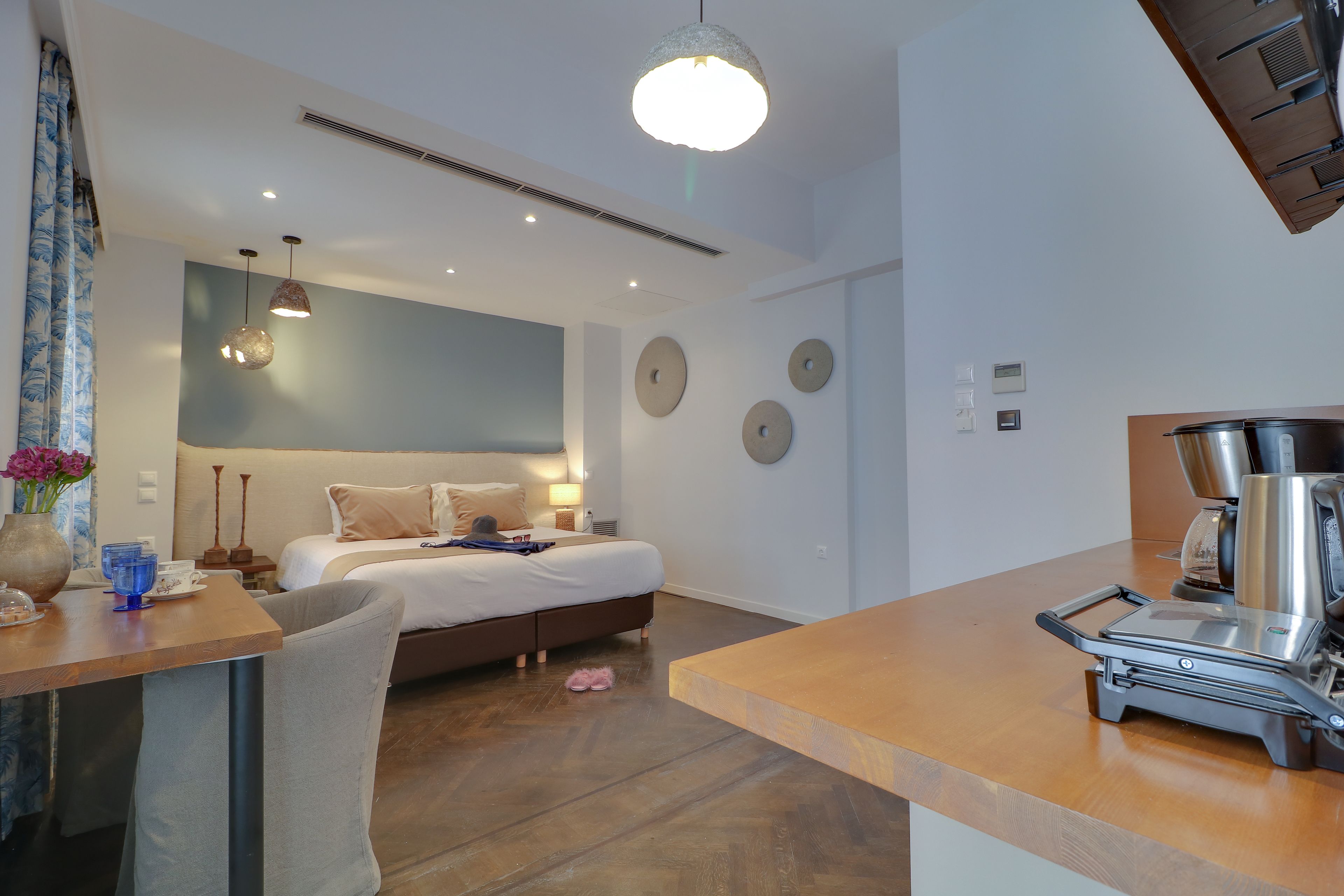 A modern hotel room with a bed, bedside table, and a kitchenette area with a coffee maker.