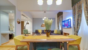 A modern living room with a wooden dining table, yellow chairs, and a green sofa set. - AthiNN Residence (Athens)