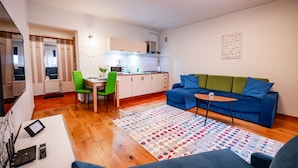 Un espace de vie compact comprenant un coin cuisine, un coin repas et un espace détente avec un canapé et une table basse.