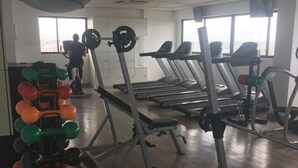 Ein Fitnessstudio mit Laufbändern, Krafttrainingsgeräten und einer Hantelbank.
