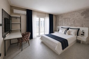 Habitación de hotel con cama, escritorio, silla, televisor y ventana con cortinas.