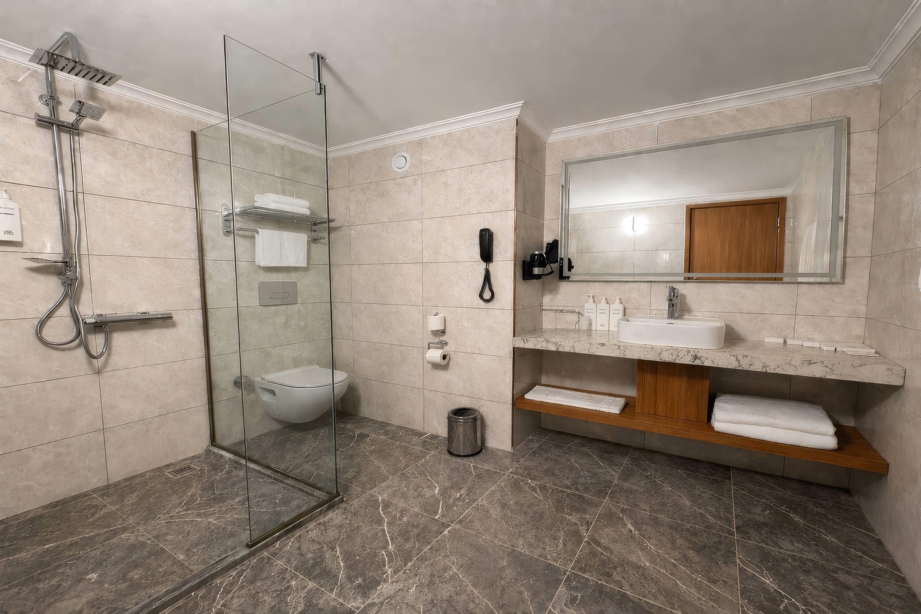 Ein modernes Badezimmer mit einer gläsernen Dusche, Toilette, Waschbecken und einem Waschtisch mit Spiegel.