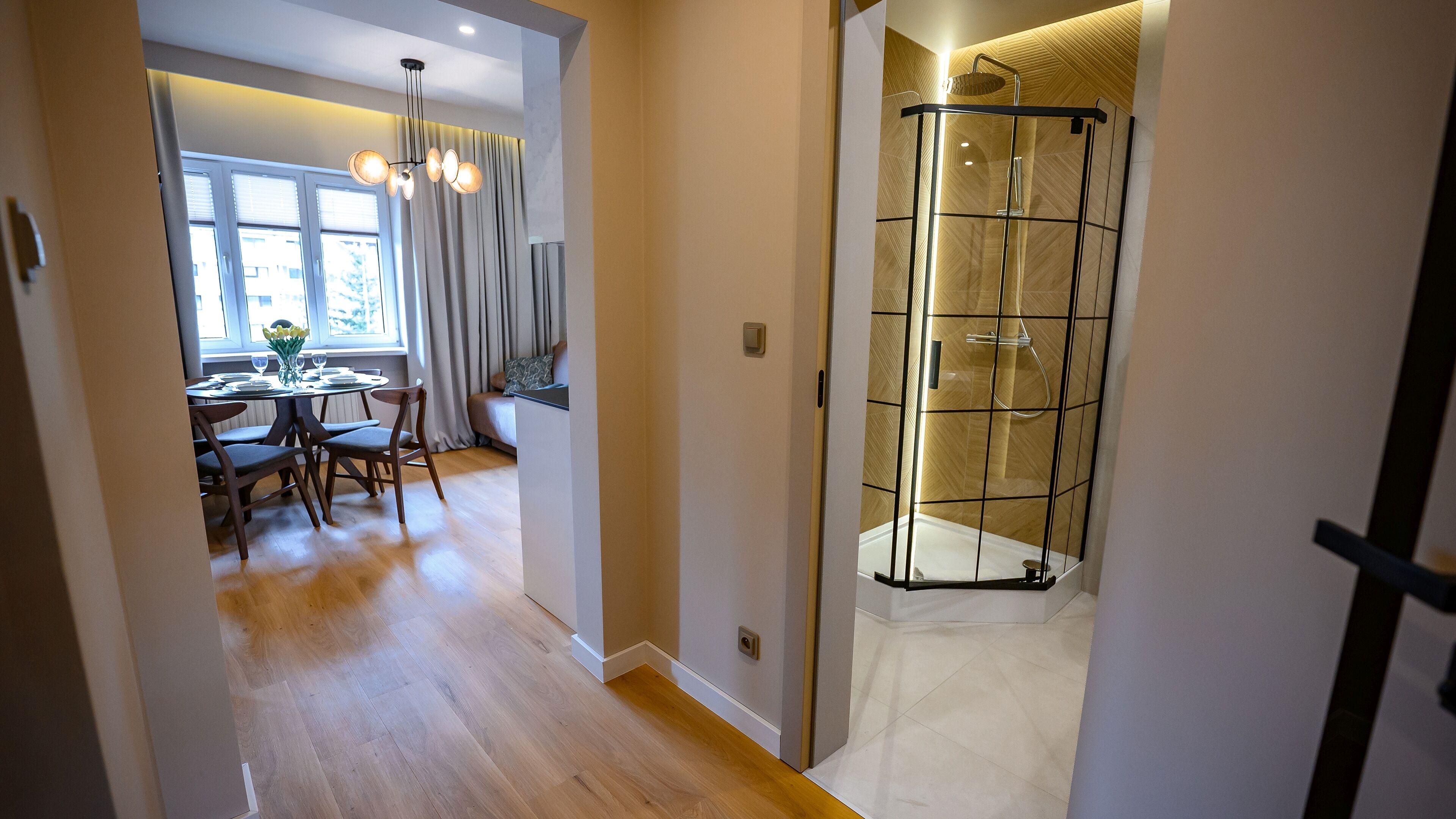 A modern bathroom with a glass-enclosed shower and a wooden floor.