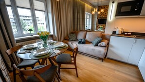 A modern living room with a dining area, a sofa, and a kitchen. - Apartamenty Sun & Snow Pułaskiego (Krynica-Zdroj)