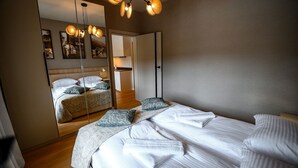 A modern bedroom with a large bed, a mirror, and a wardrobe. - Apartamenty Sun & Snow Pułaskiego (Krynica-Zdroj)