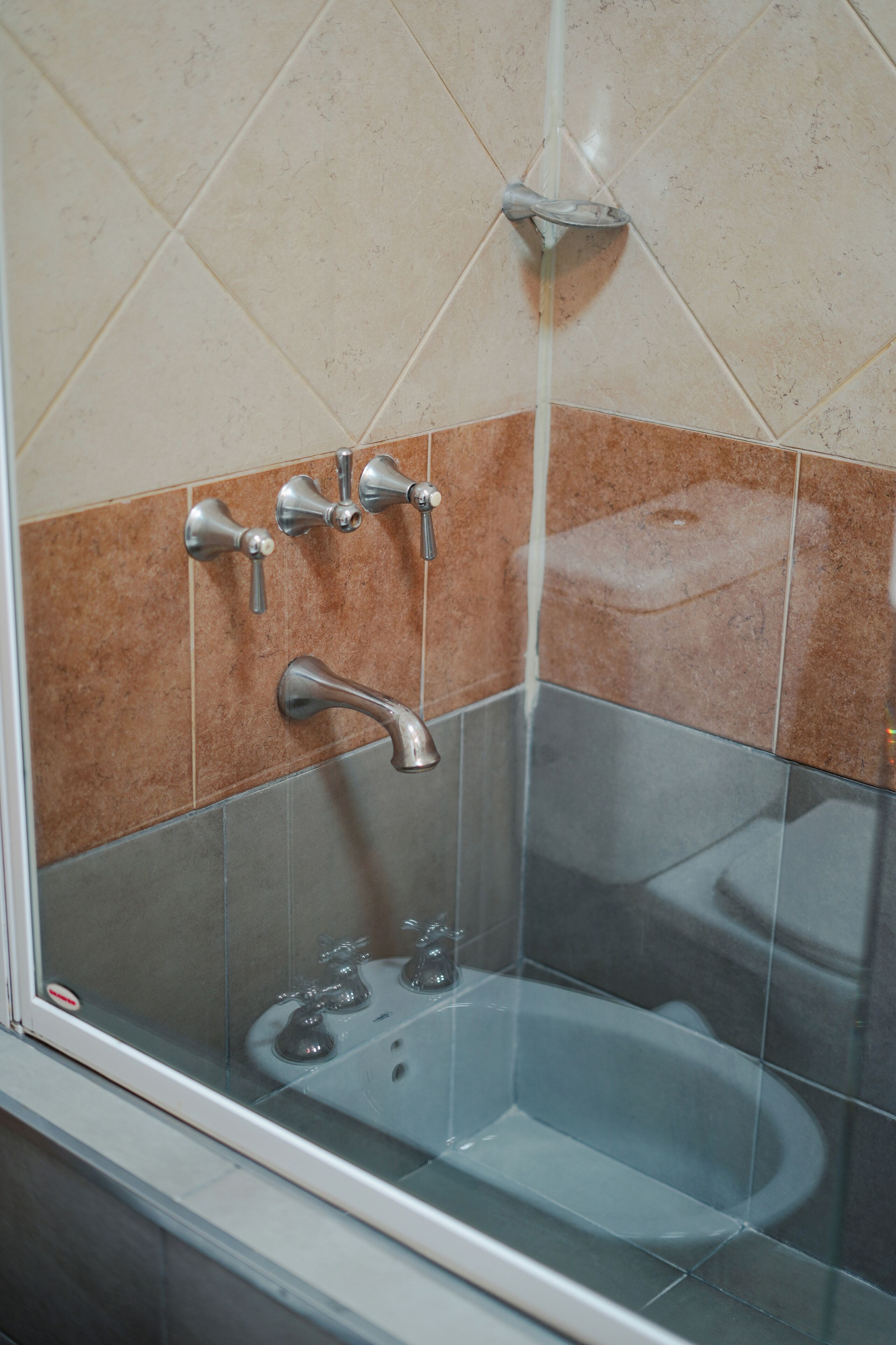 A bathroom with a glass-enclosed shower, a wall-mounted faucet, and a bathtub.