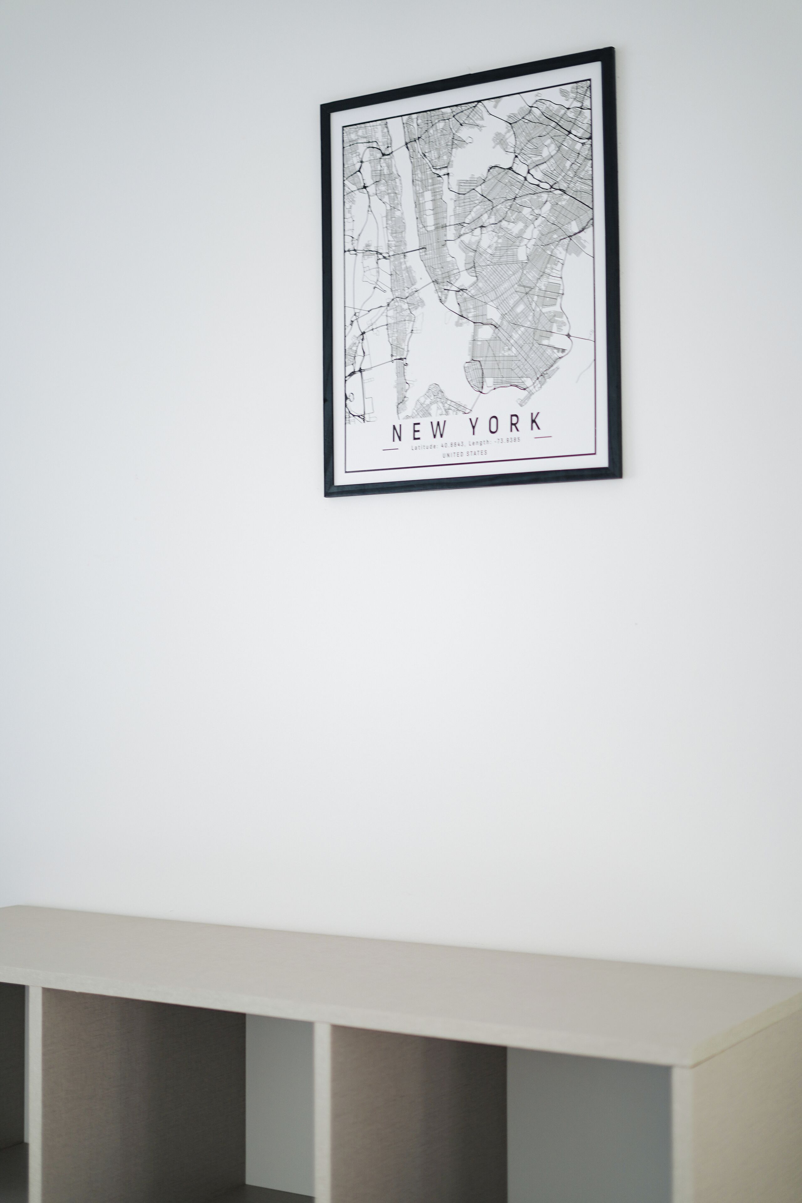 A framed black and white map of New York City on a white wall.