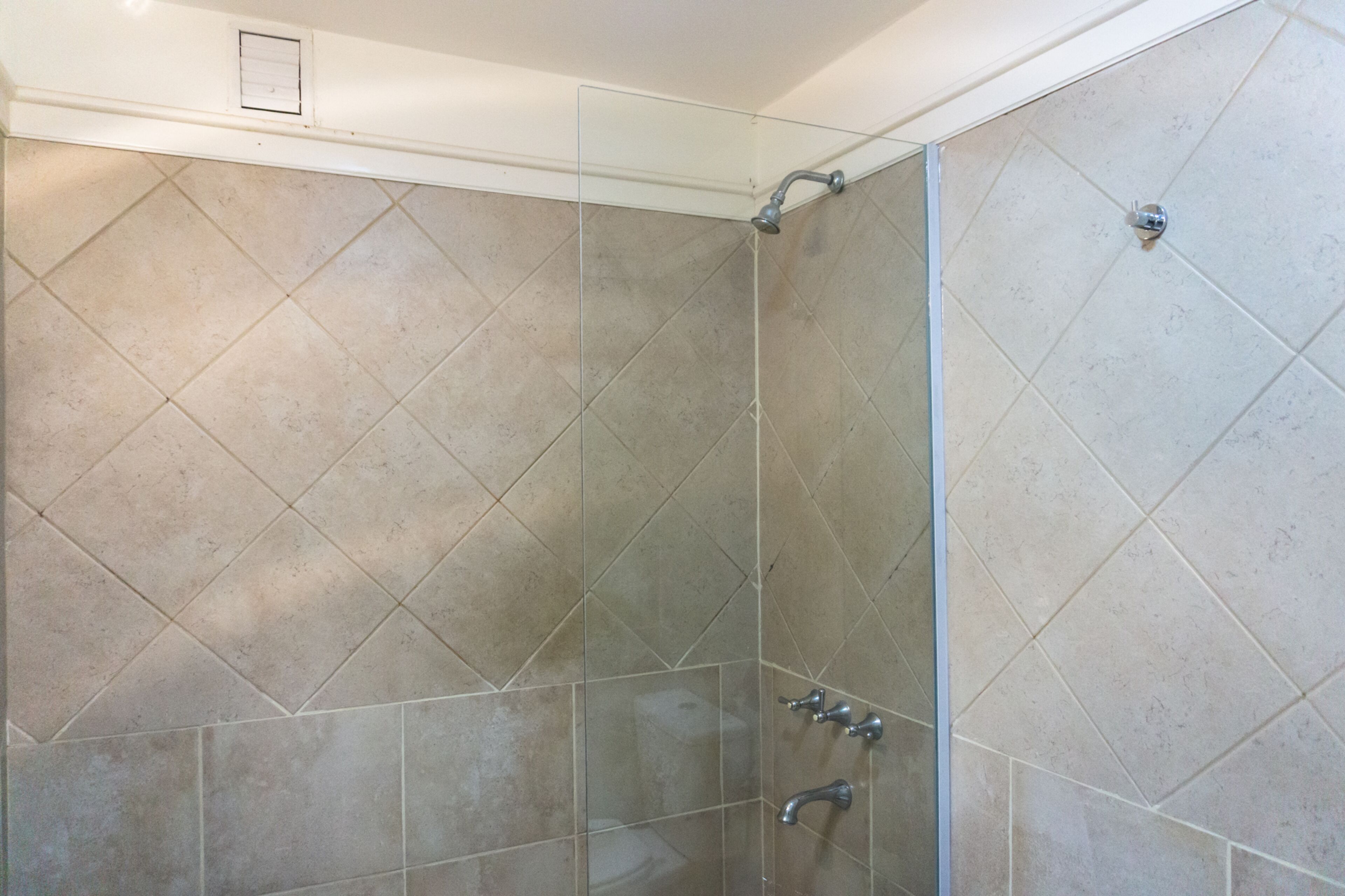 A shower area with tiled walls and a glass partition.