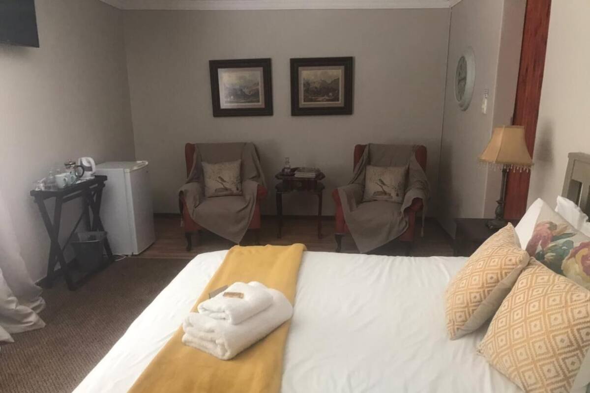 Een hotelkamer met een bed, twee fauteuils, een kleine tafel en een bureau met een computer en een lamp.