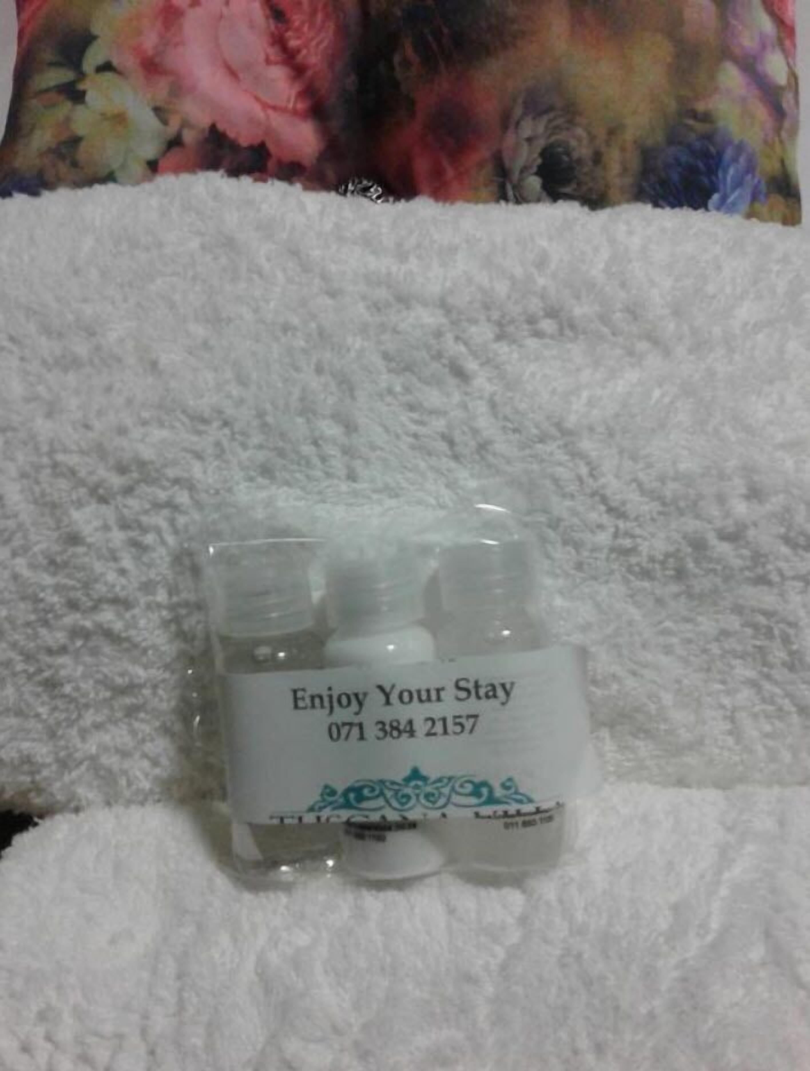 A small, clear plastic container with a label that reads "Enjoy Your Stay" and a phone number.