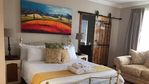 A neatly arranged bedroom with a bed, bedside table, lamp, and a painting on the wall.