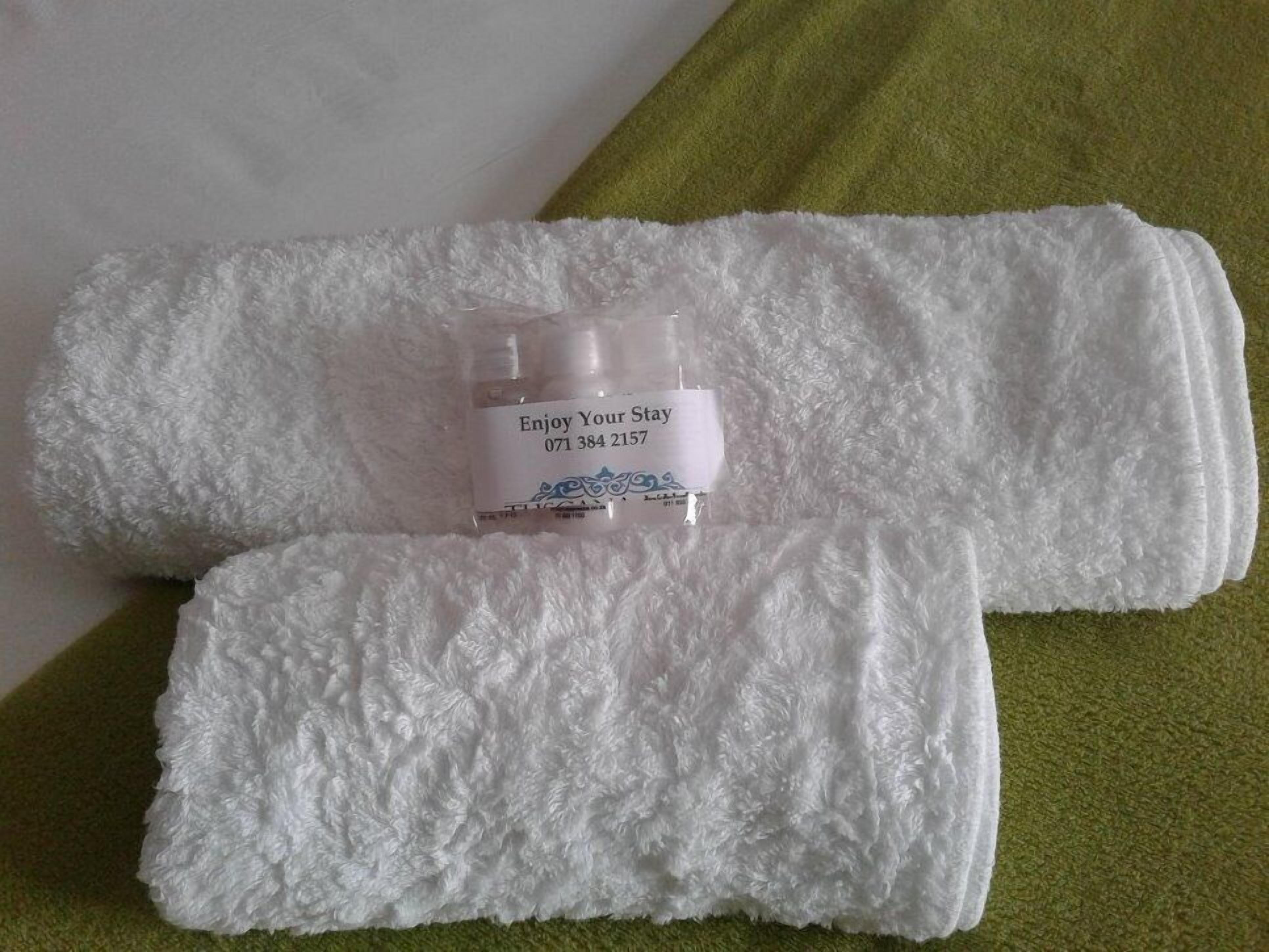 Una toalla blanca y un pequeño recipiente con una etiqueta sobre una superficie verde.