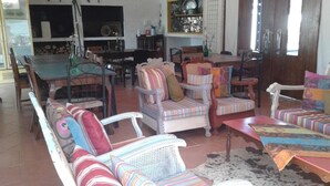 A spacious living area with a sofa set, a dining table, and chairs.