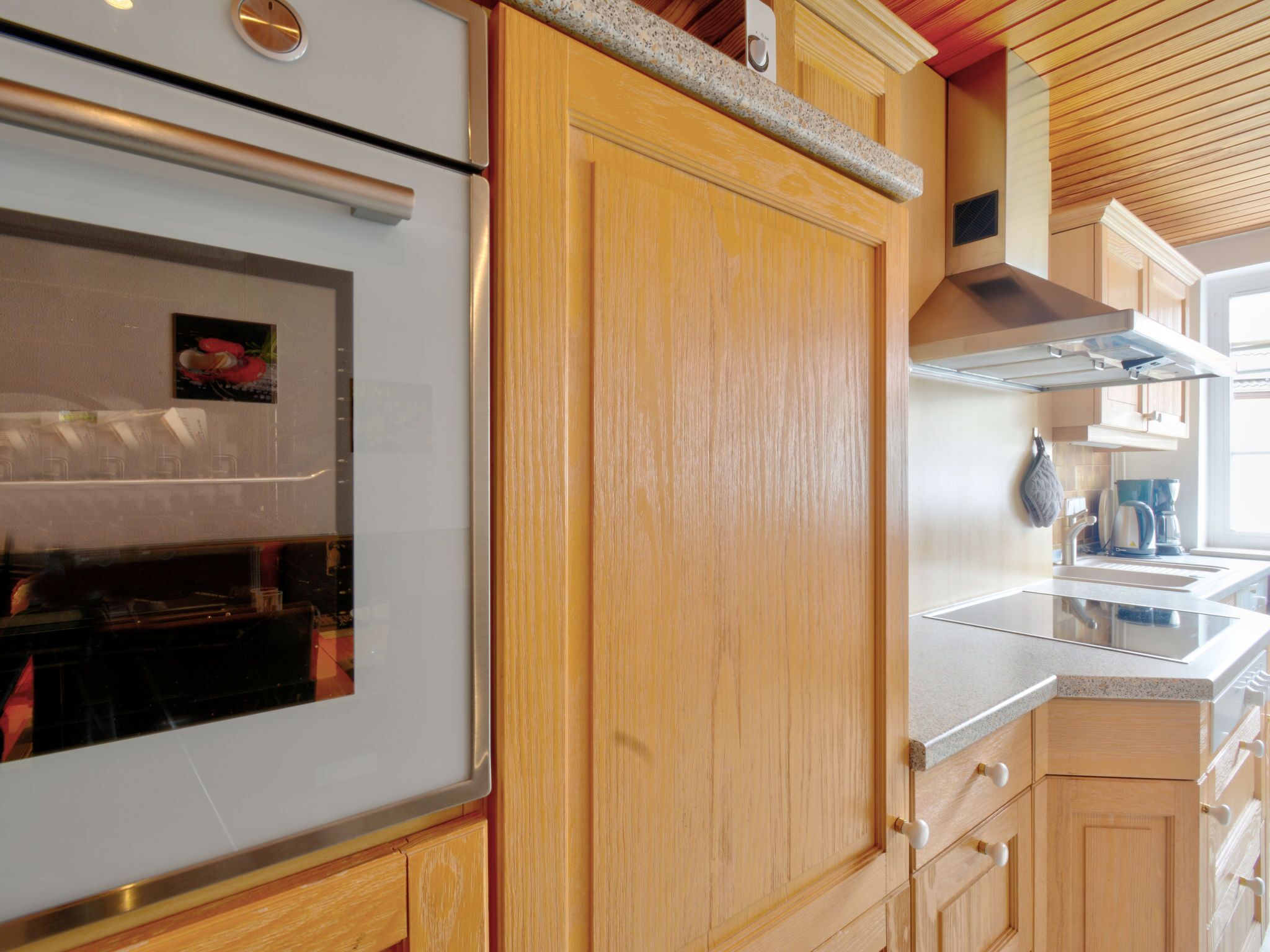 Une cuisine avec des meubles en bois, un four en acier inoxydable et un plan de travail en granit.
